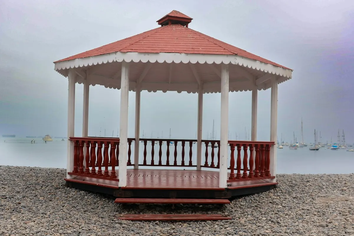 Red-and-white gazebo with a pitched roof beside the shore