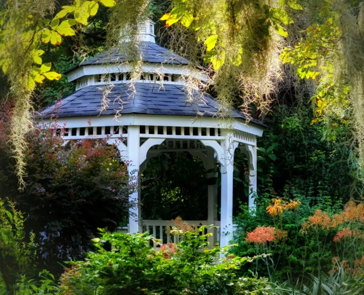 Ornate white garden gazebo surrounded by trees